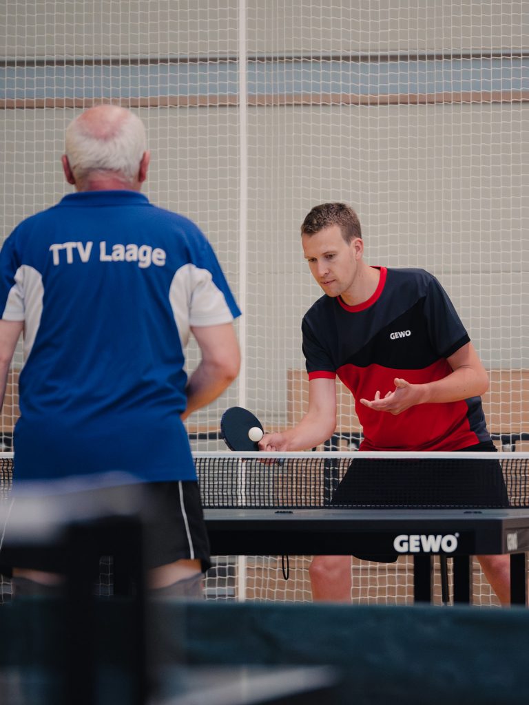 Zwei Männer stehen sich an der Tischtennisplatte gegenüber und spielen Tischtennis gegeneinander.