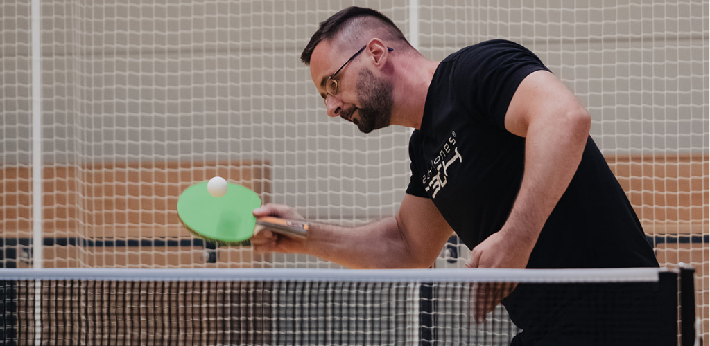 Ein Mann spielt einen Tischtennisball über die Platte.
